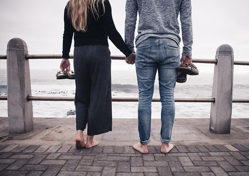 Un couple se tient la main face à la mer